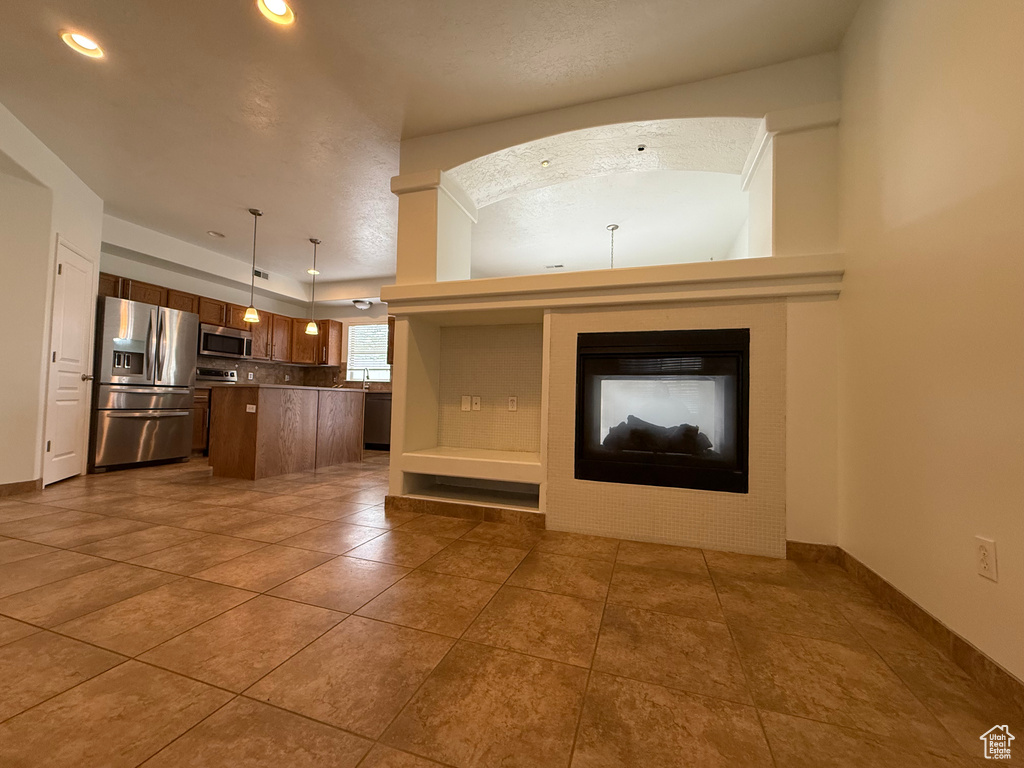 Unfurnished living room featuring dark tile patterned flooring, baseboards, recessed lighting, and a glass covered fireplace