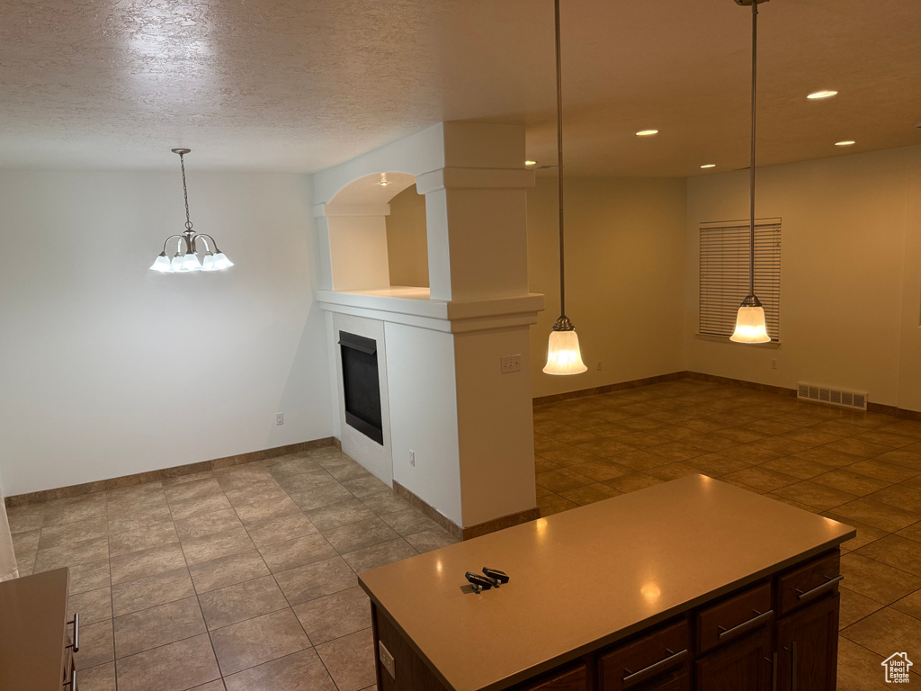 Kitchen with a glass covered fireplace, recessed lighting, light countertops, baseboards, and hanging light fixtures