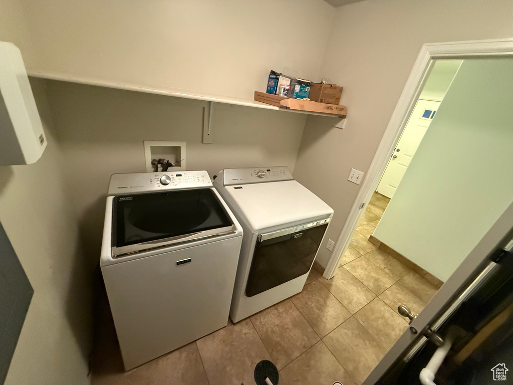 Laundry room featuring washer and dryer, light tile patterned floors, and baseboards