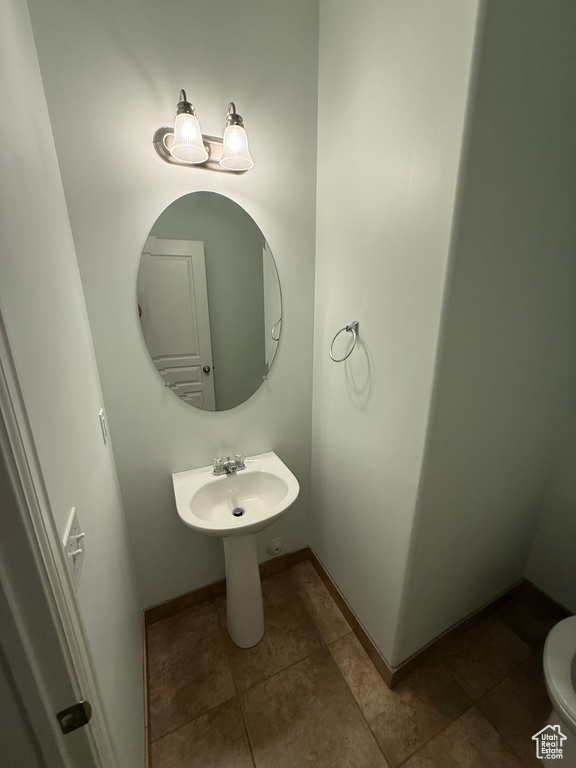 Half bath with baseboards and tile patterned flooring