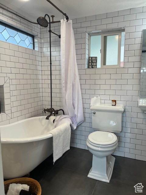 Full bathroom featuring toilet, tile walls, tile patterned flooring, and tiled shower / bath combo