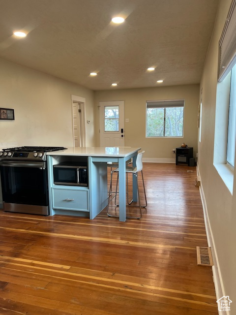 Kitchen with stainless steel appliances, recessed lighting, hardwood / wood-style floors, baseboards, and light countertops