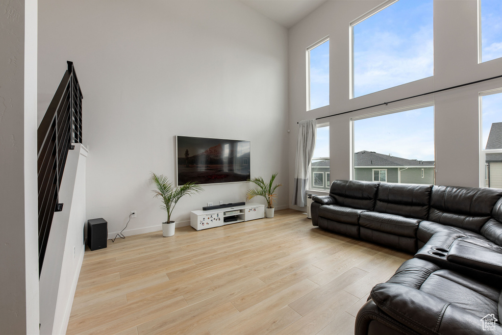 Living room featuring a high ceiling, wood finished floors, healthy amount of natural light, and baseboards