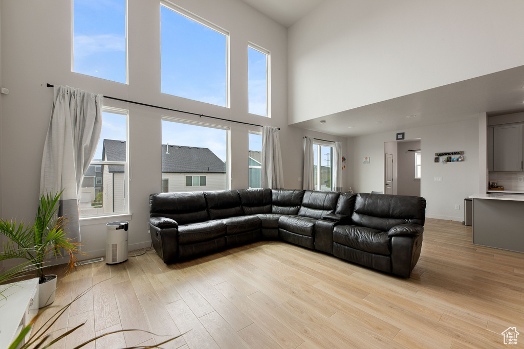 Living area with light wood-style floors, baseboards, and a high ceiling