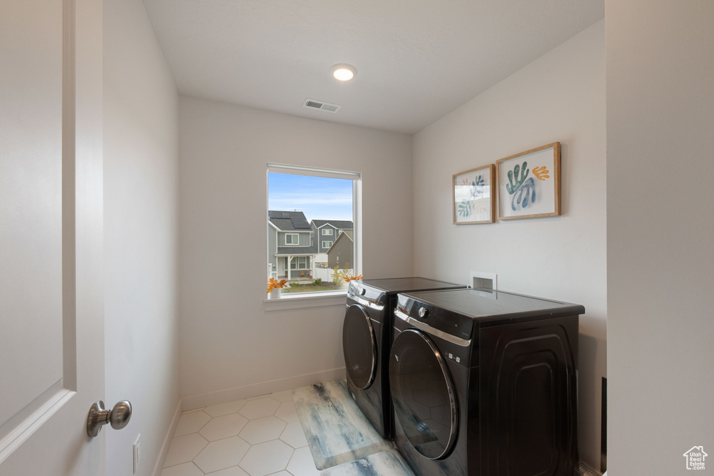 Laundry room featuring washer and dryer, tile patterned floors, and baseboards