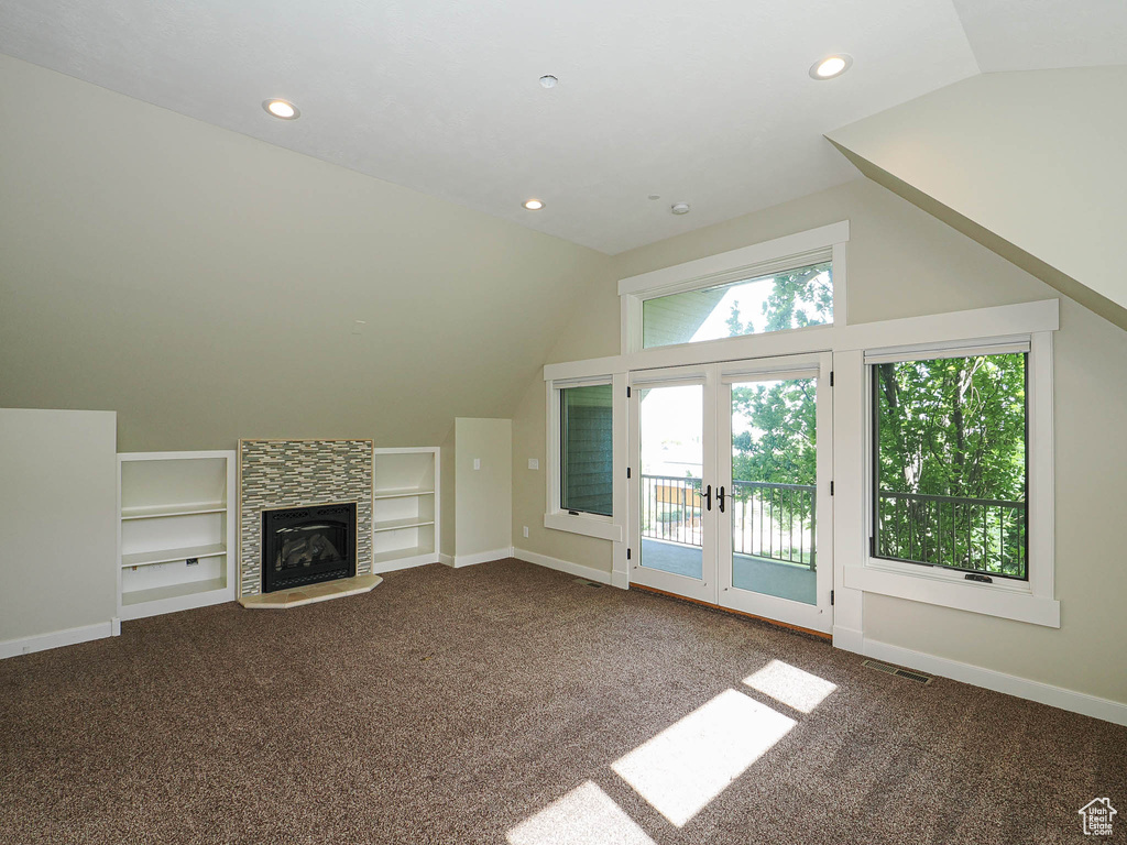 Unfurnished living room featuring vaulted ceiling, built in features, carpet floors, recessed lighting, and french doors