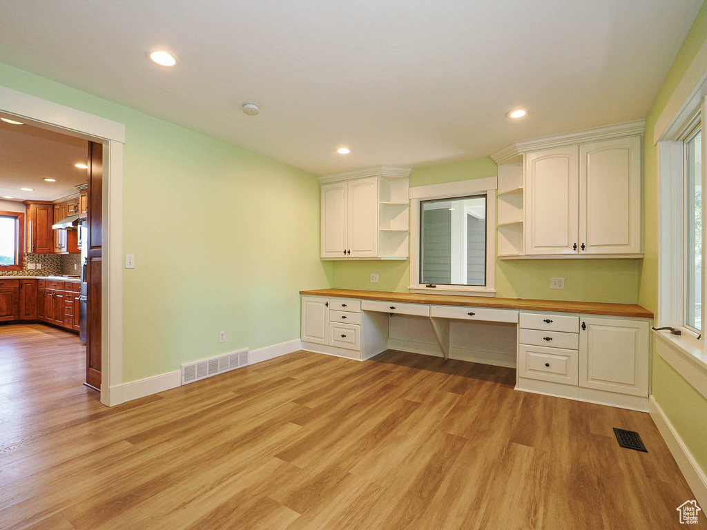 Unfurnished office featuring built in study area, light wood-style flooring, baseboards, and recessed lighting