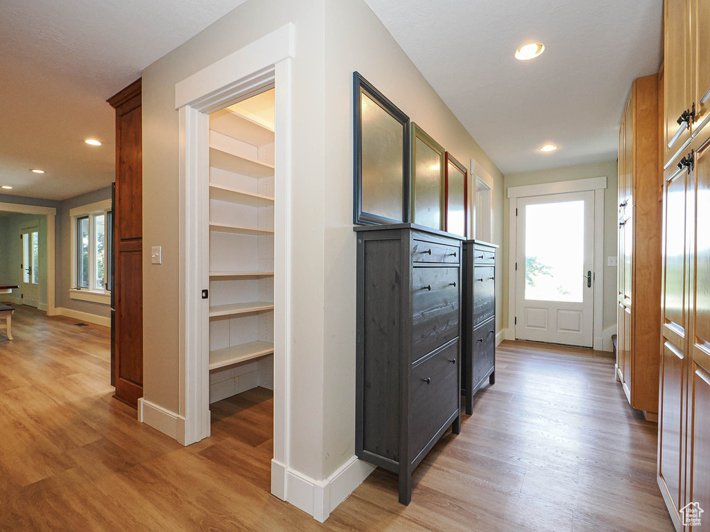 Hall with light wood-style floors, healthy amount of natural light, baseboards, recessed lighting, and built in shelves