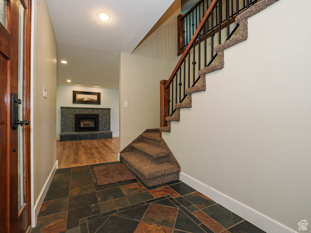 Entrance foyer with baseboards, stone tile flooring, stairway, a fireplace, and recessed lighting