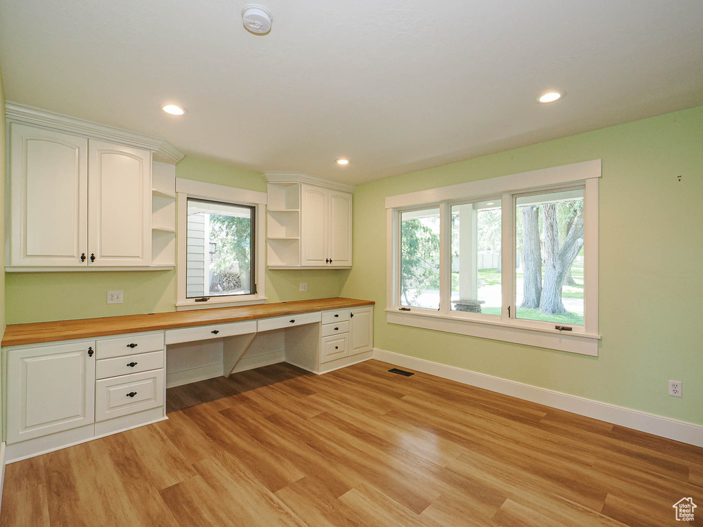 Unfurnished office featuring built in desk, baseboards, plenty of natural light, light wood-type flooring, and recessed lighting