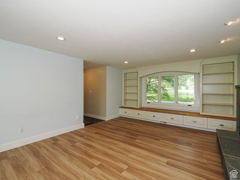 Unfurnished living room with baseboards, light wood-type flooring, built in features, and recessed lighting