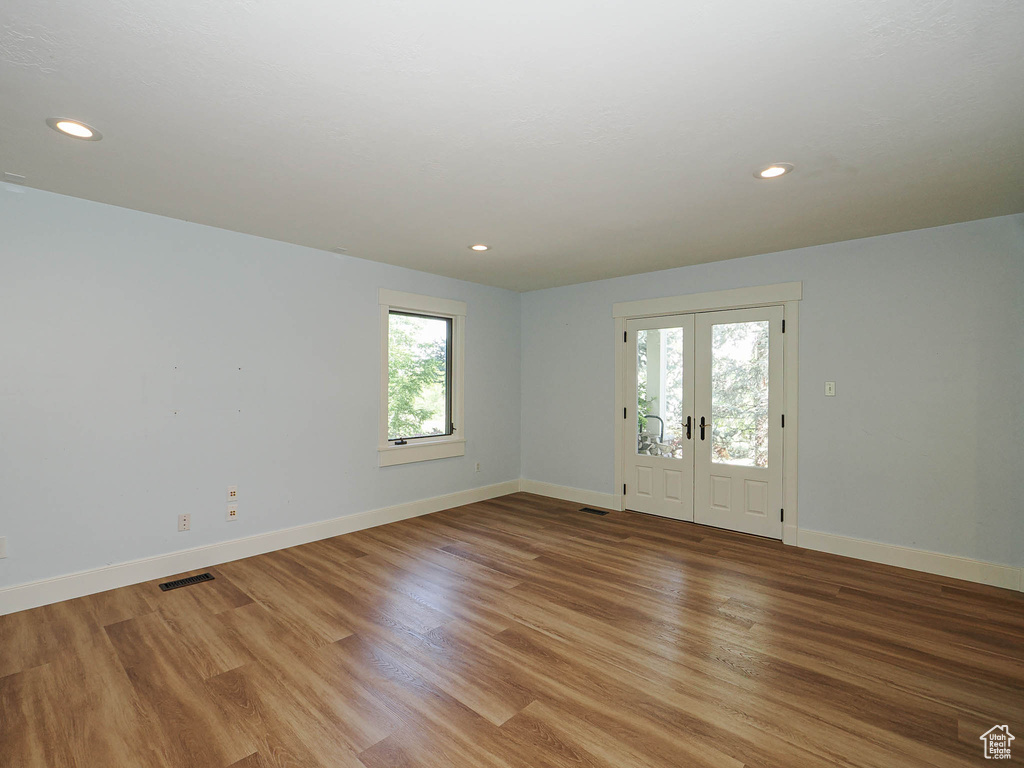 Empty room with baseboards, light wood finished floors, recessed lighting, and french doors
