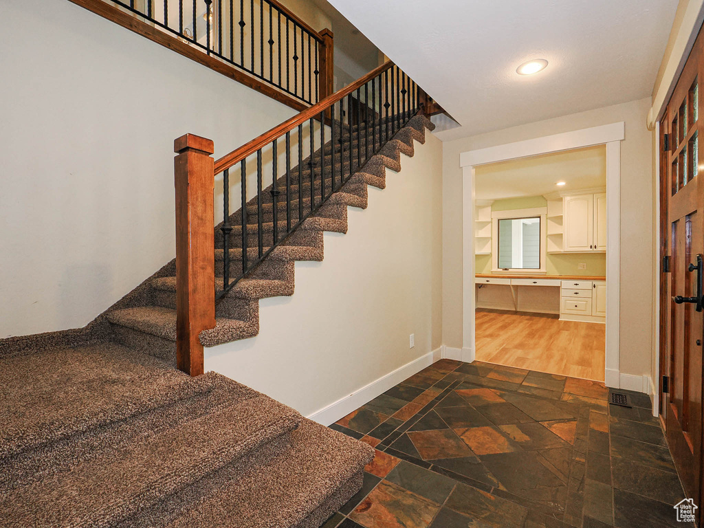 Staircase with stone tile flooring, baseboards, recessed lighting, and built in desk