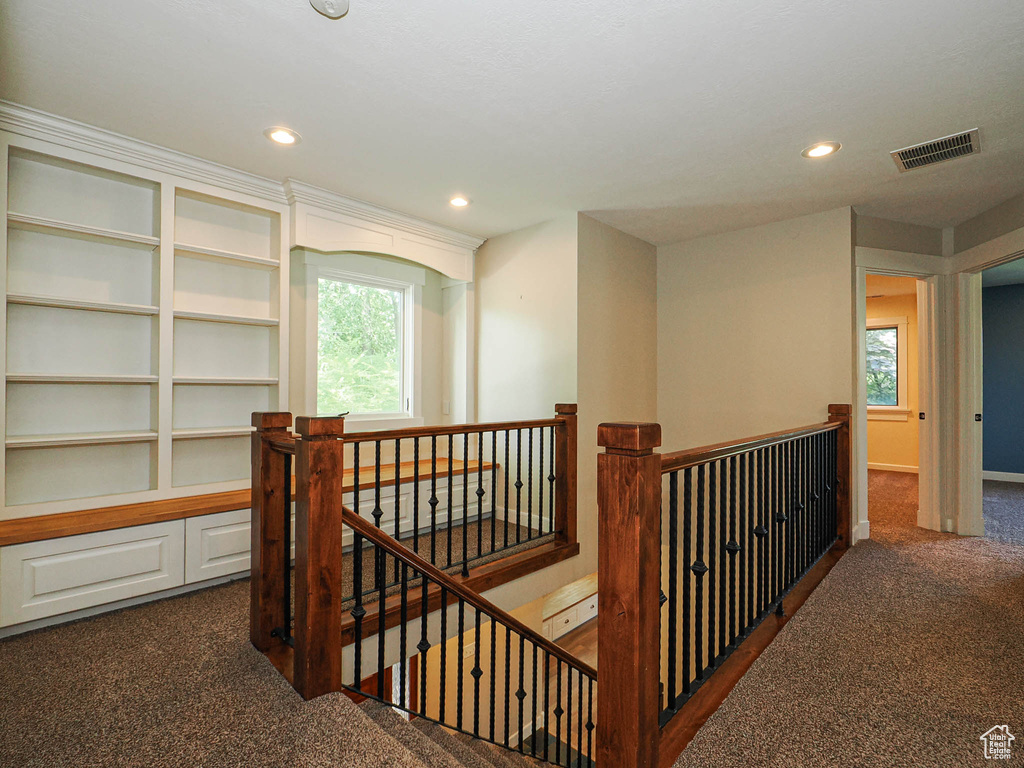 Hall with an upstairs landing, dark carpet, and recessed lighting