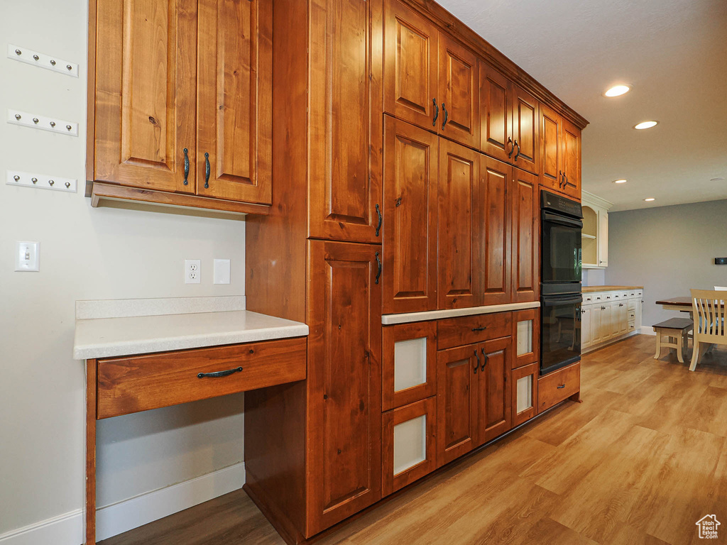 Kitchen with light wood finished floors, baseboards, brown cabinetry, recessed lighting, and light countertops