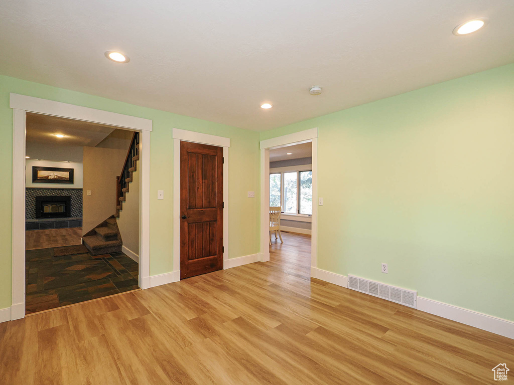 Unfurnished room featuring light wood-type flooring, stairway, a fireplace, recessed lighting, and baseboards