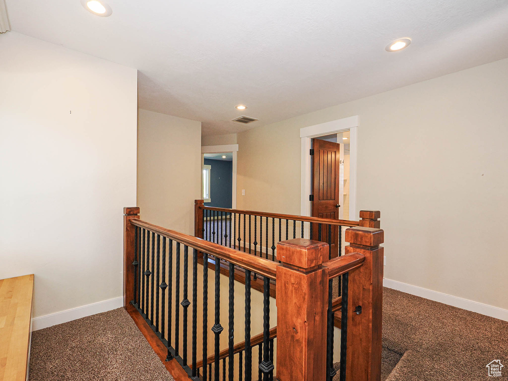Hallway with an upstairs landing, carpet floors, baseboards, and recessed lighting