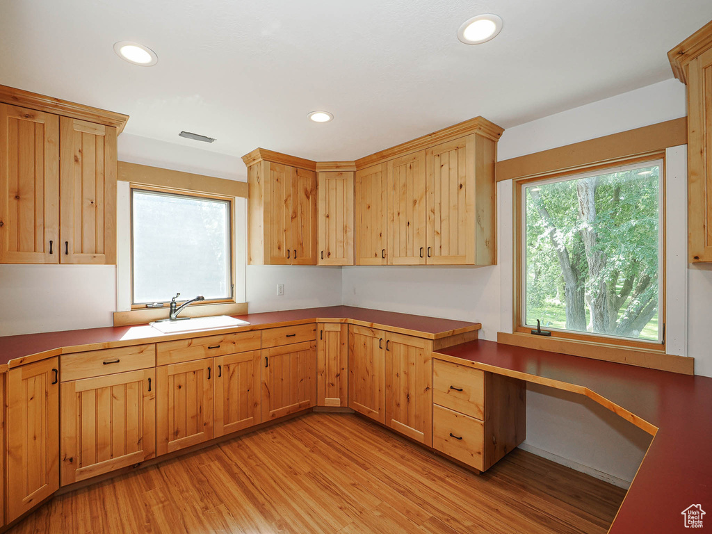 Kitchen featuring a sink, light wood-style flooring, recessed lighting, light brown cabinets, and a desk