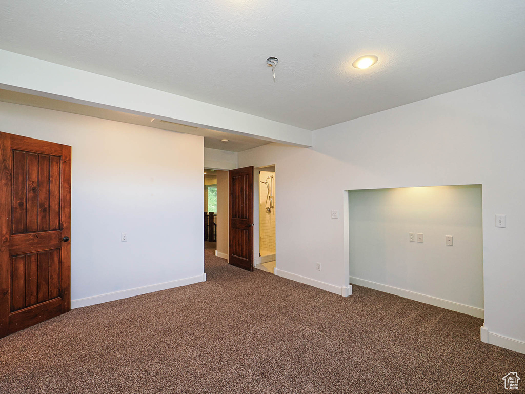 Spare room featuring dark carpet and baseboards
