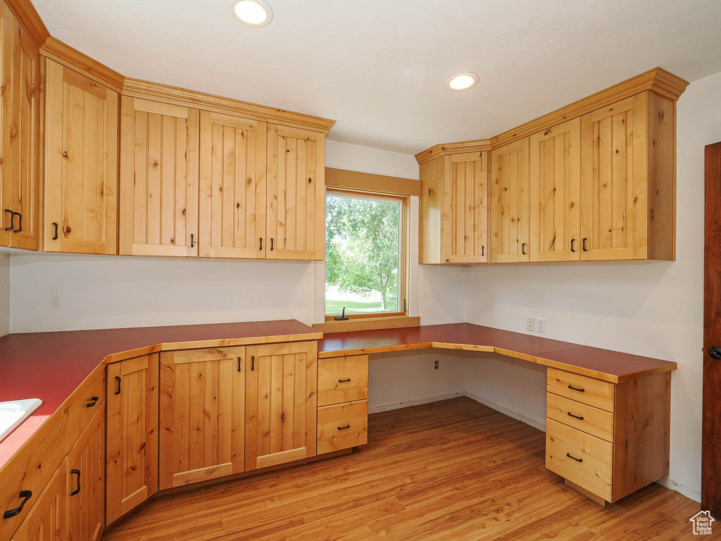 Unfurnished office featuring built in desk, light wood-style flooring, and recessed lighting