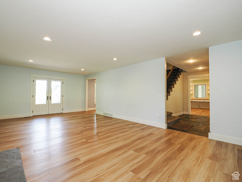 Unfurnished living room featuring light wood-type flooring, stairway, baseboards, and recessed lighting