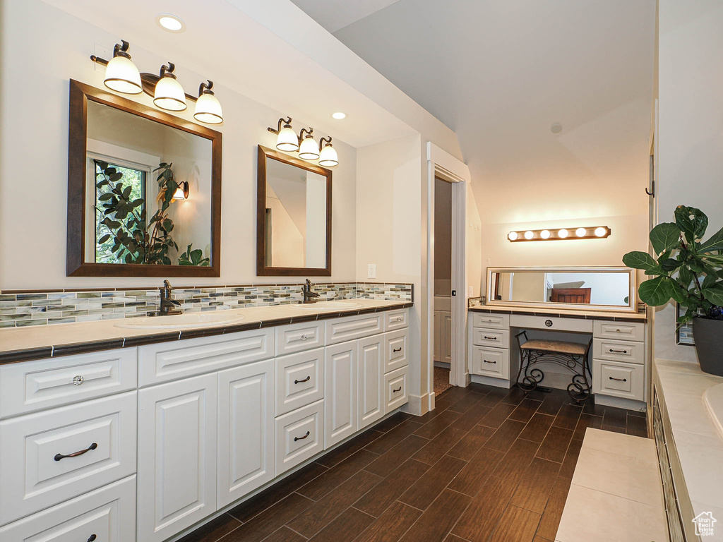 Bathroom featuring double vanity, tasteful backsplash, a tub, wood finished floors, and recessed lighting