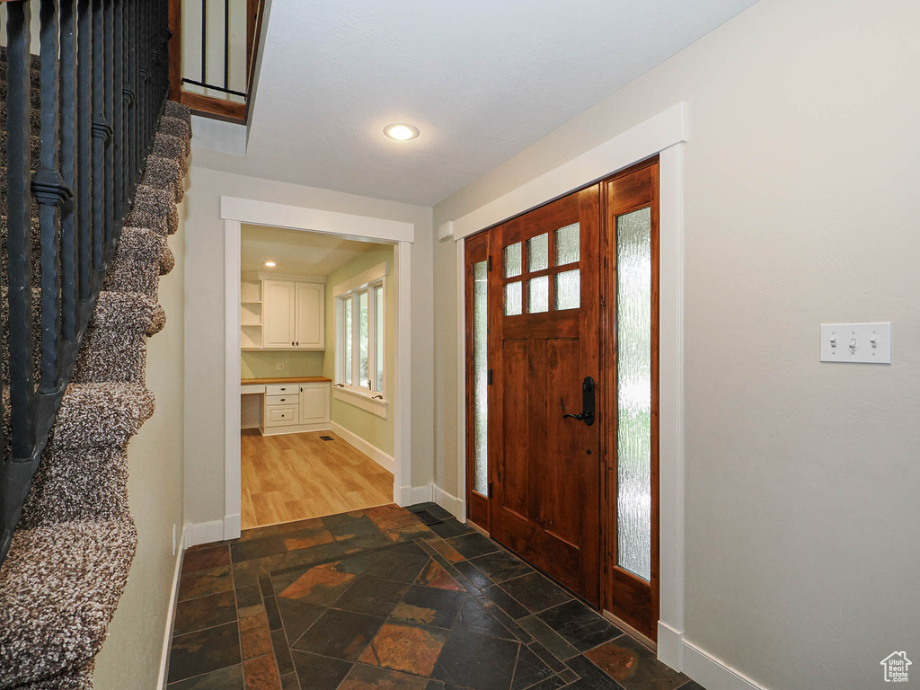 Entryway featuring dark stone finish flooring, baseboards, stairway, and recessed lighting