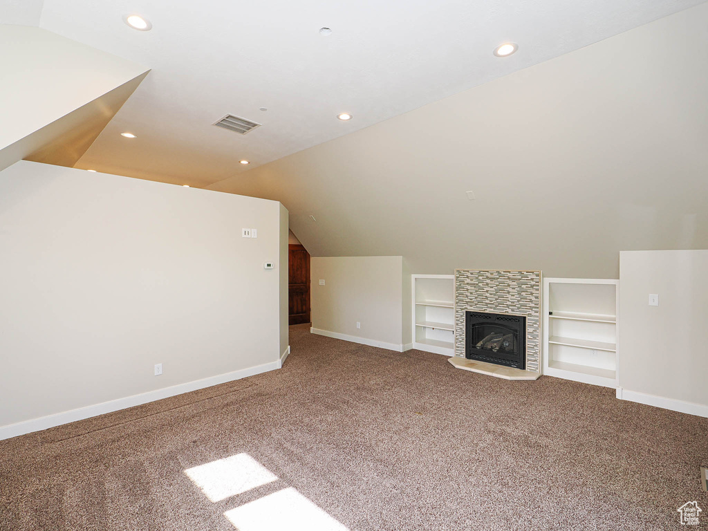 Unfurnished living room with carpet floors, built in features, baseboards, lofted ceiling, and recessed lighting
