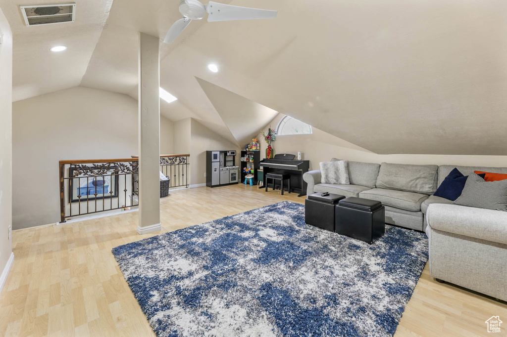 Living room with vaulted ceiling, wood finished floors, baseboards, and recessed lighting