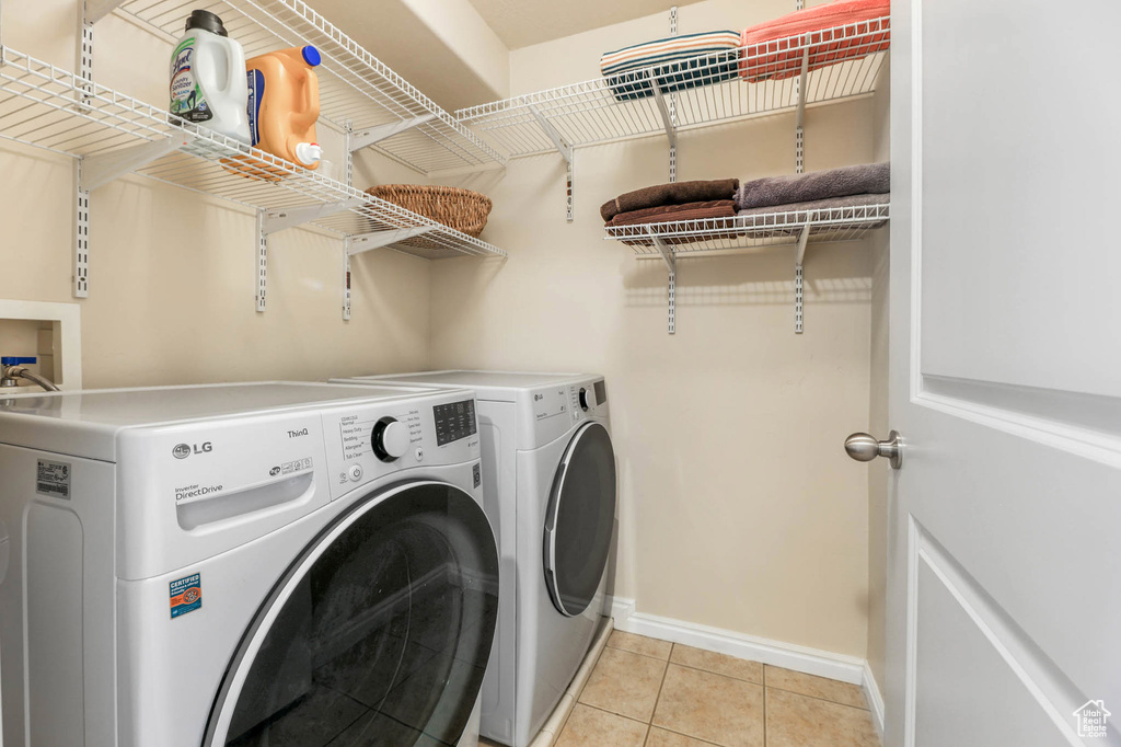 Laundry room featuring separate washer and dryer, baseboards, and light tile patterned flooring