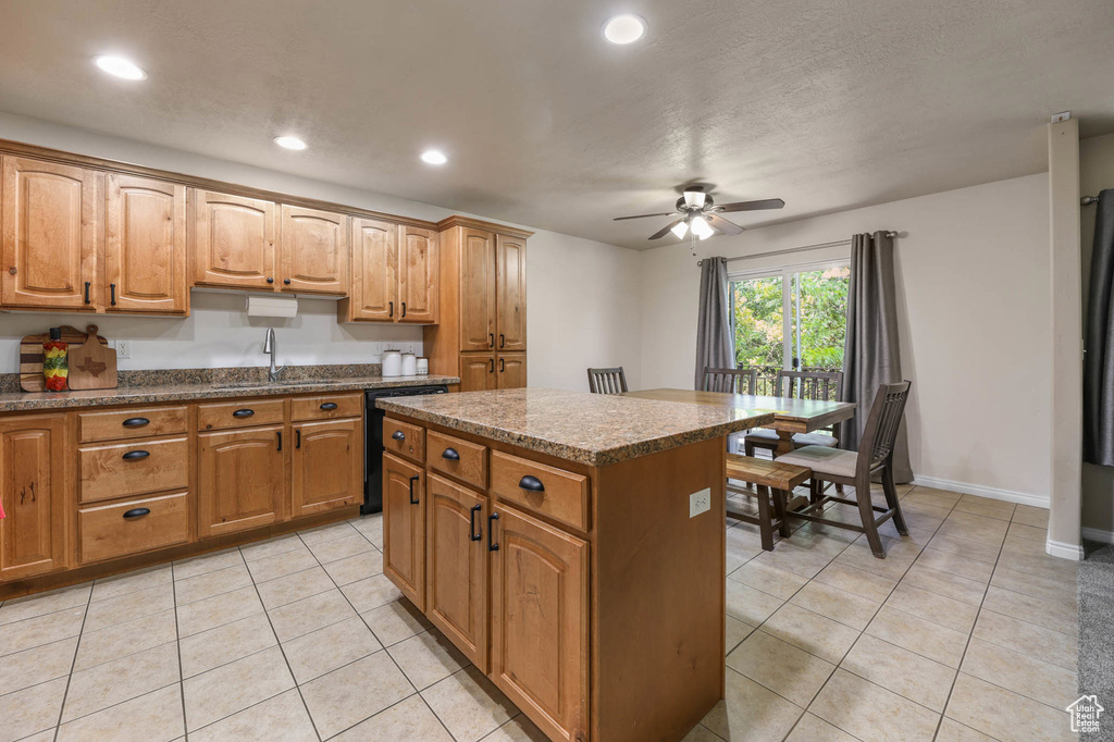 Kitchen featuring a sink, dishwasher, a ceiling fan, light tile patterned floors, and a center island