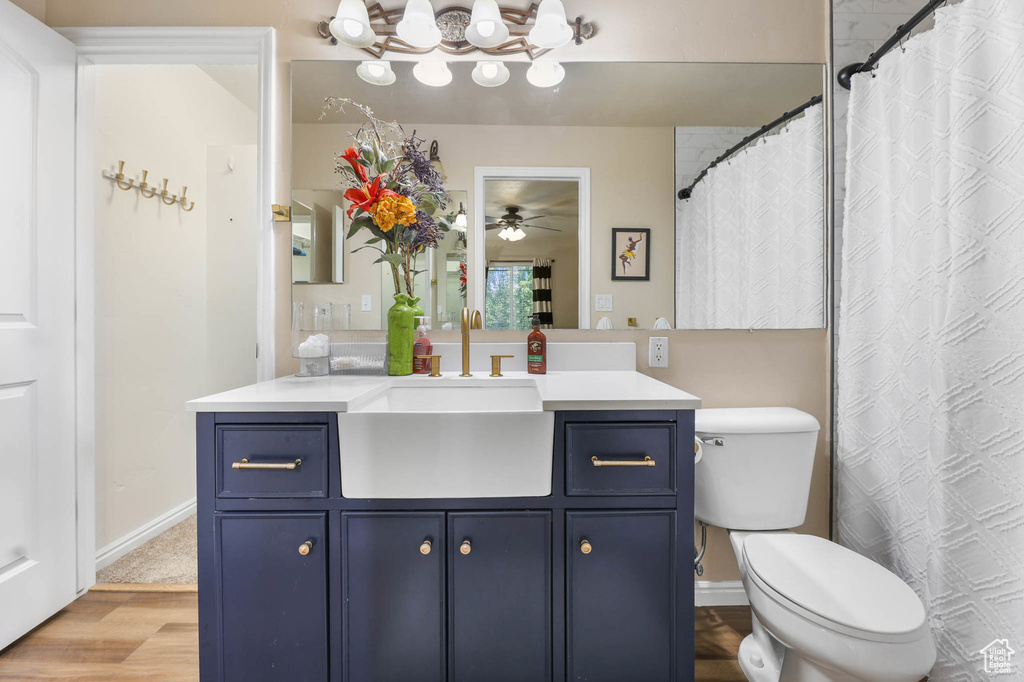 Full bath with vanity, wood finished floors, ceiling fan, a chandelier, and toilet