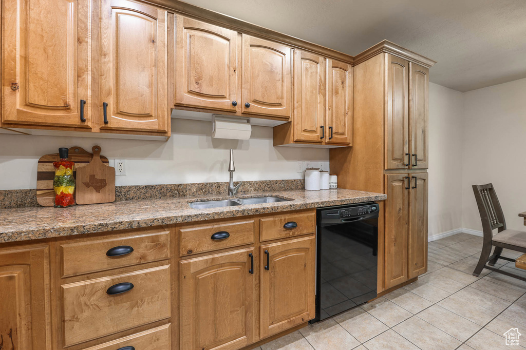 Kitchen featuring dishwasher, a sink, light tile patterned floors, and light stone countertops
