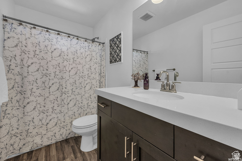 Bathroom with vanity, wood finished floors, toilet, and a shower with shower curtain