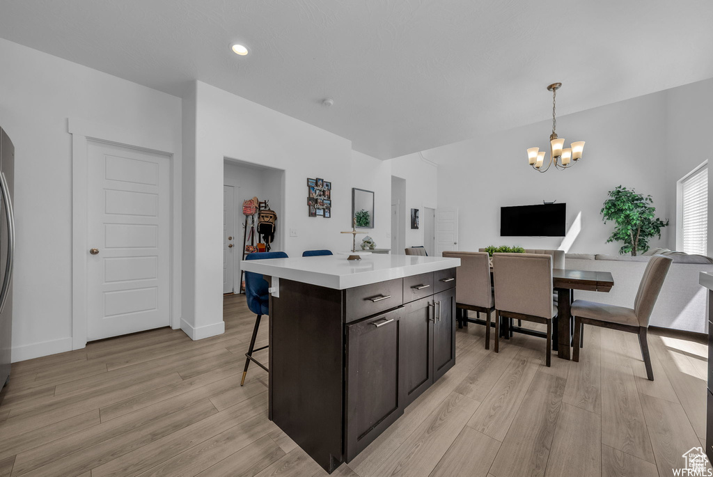 Kitchen featuring a chandelier, light wood-type flooring, light countertops, a center island, and a breakfast bar