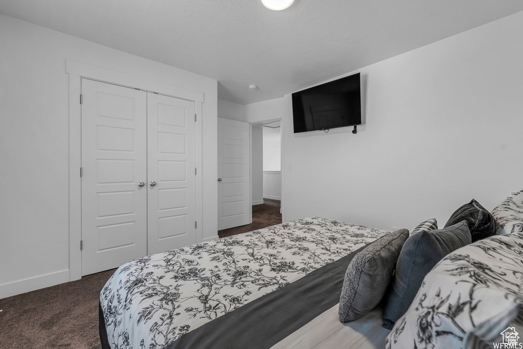 Bedroom featuring a closet, dark colored carpet, and baseboards
