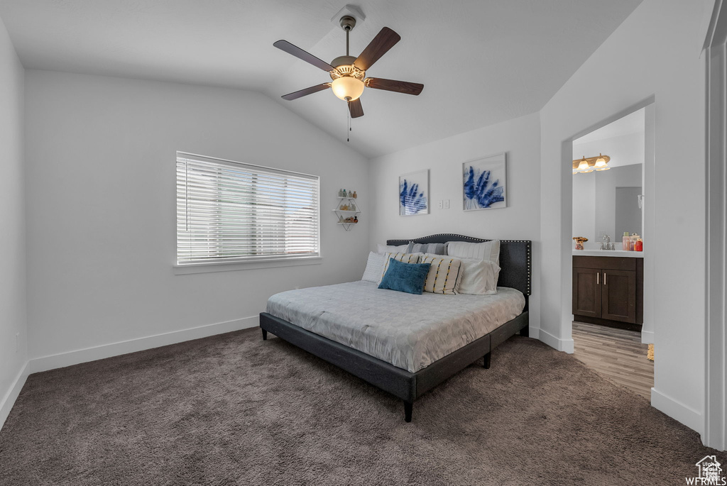 Carpeted bedroom with vaulted ceiling, baseboards, a ceiling fan, and ensuite bathroom