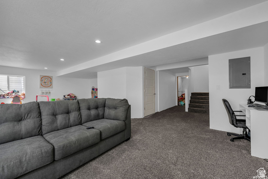 Living room featuring electric panel, dark colored carpet, recessed lighting, stairway, and a desk