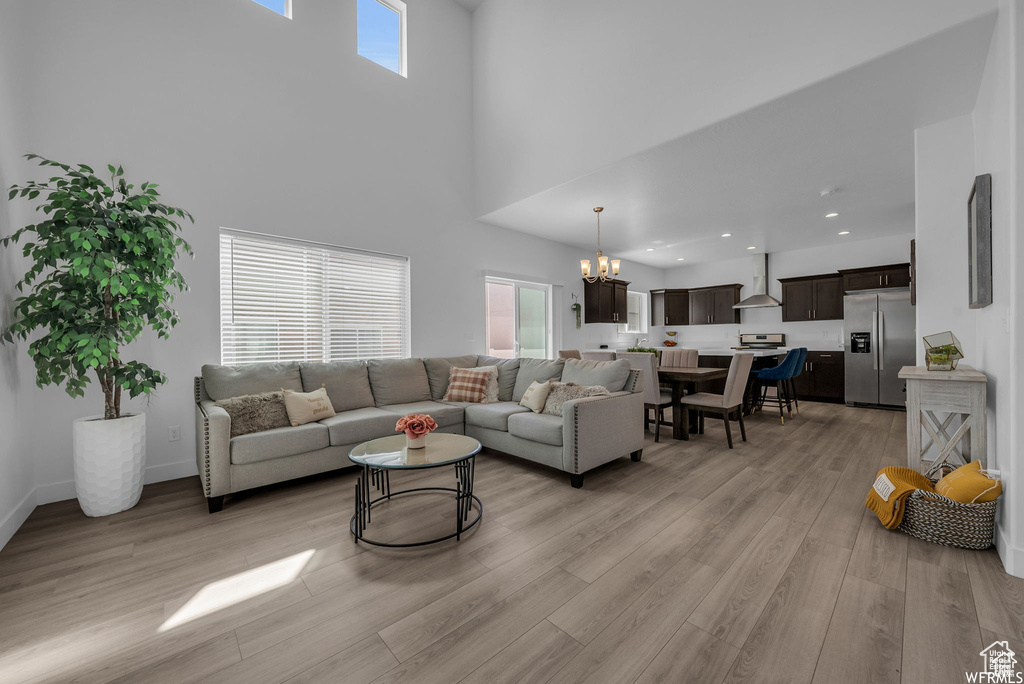 Living room featuring a chandelier, a towering ceiling, light wood finished floors, and recessed lighting