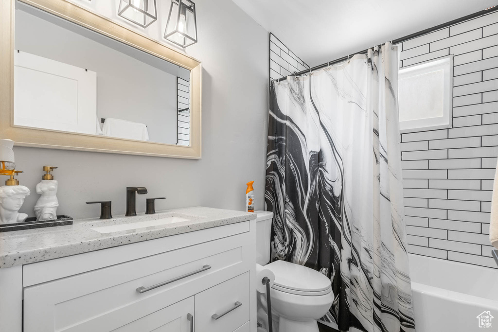 Full bathroom featuring vanity, toilet, and shower / bath combination with curtain
