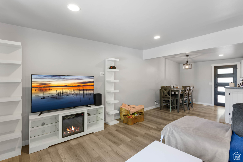 Living room featuring wood finished floors, baseboards, recessed lighting, and a glass covered fireplace