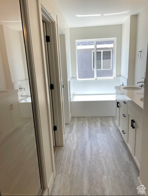 Bathroom featuring wood finished floors, a bath, and double vanity