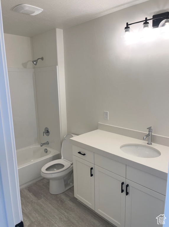 Full bathroom with wood finished floors, vanity, toilet, and bathing tub / shower combination