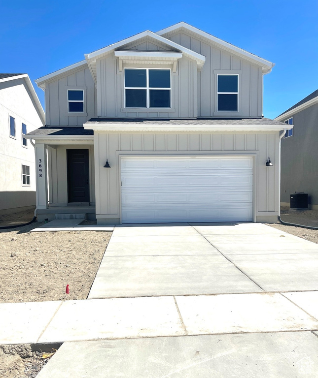 View of front of house featuring board and batten siding, a garage, driveway, and central air condition unit