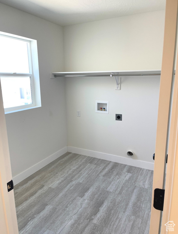 Laundry area with wood finished floors, hookup for a washing machine, electric dryer hookup, and baseboards