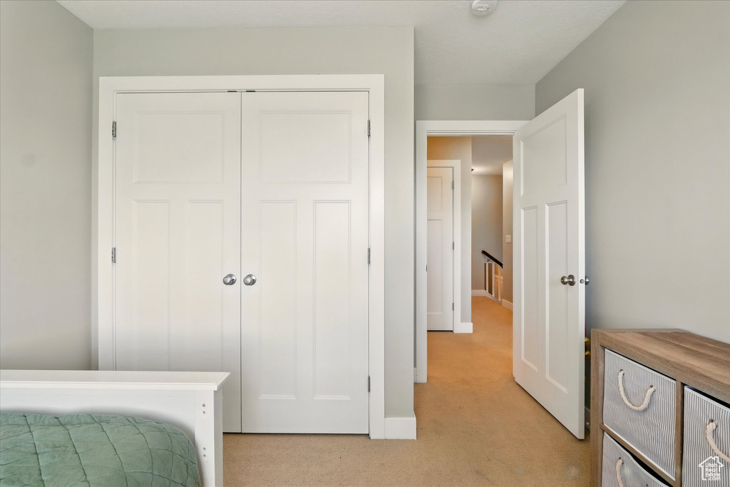 Bedroom with light carpet, a closet, and baseboards