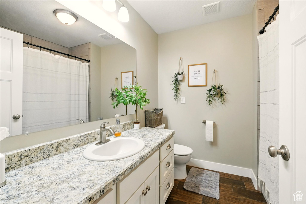 Full bathroom featuring wood finished floors, baseboards, vanity, and toilet