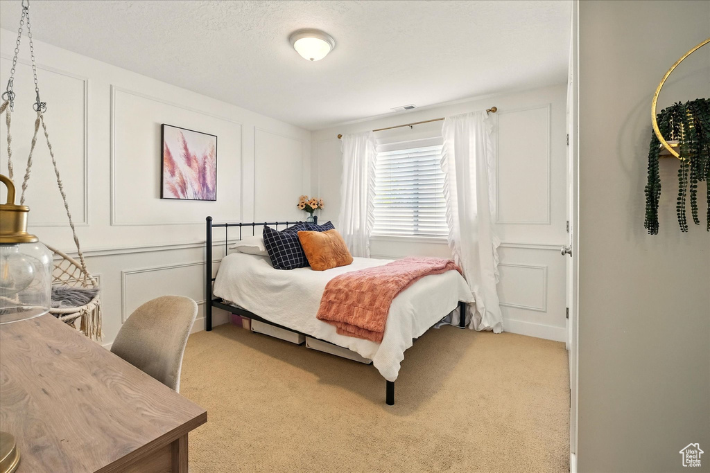 Bedroom featuring carpet flooring and a decorative wall