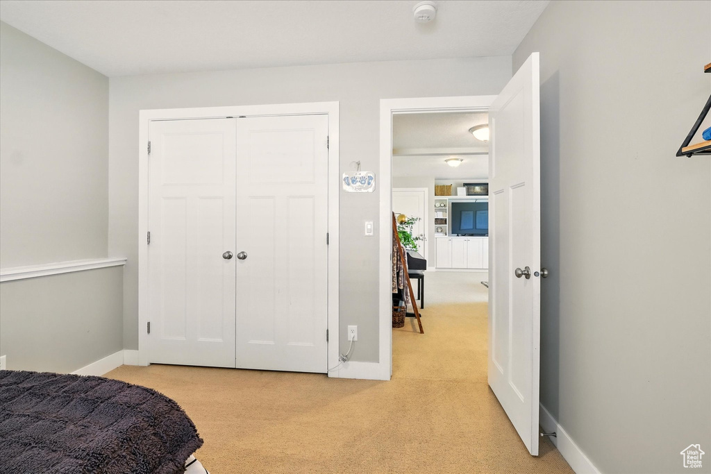 Bedroom with light carpet, baseboards, and a closet