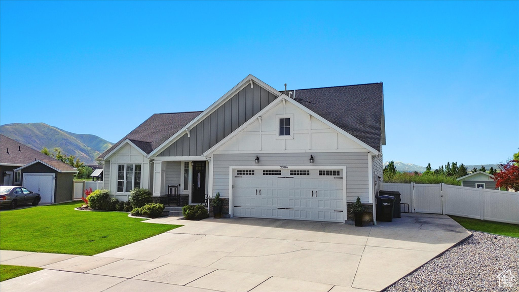 View of front of property featuring board and batten siding, a garage, a gate, a mountain view, and driveway